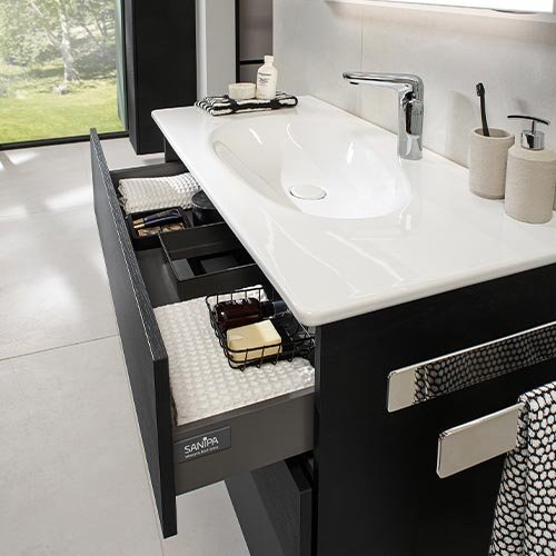 Ein modernes Badezimmer mit einem eleganten Waschbecken und offenen Schubladen, die Pflegeprodukte zeigen.