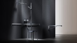 Der Raum zeigt eine stilvolle Duschinstallation mit minimalistischen Linien und einem praktischen Hocker für Komfort und Unterstützung.